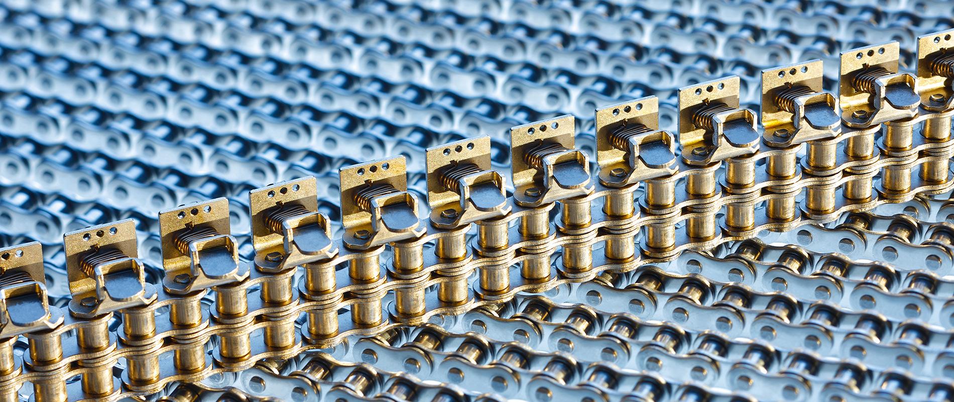Nahaufnahme einer Reihe goldfarbener Verbindungsstücke, die auf einer blauen Oberfläche angeordnet sind. Die Struktur zeigt detaillierte Metallteile in regelmäßigen Abständen, die harmonisch miteinander verbunden sind.